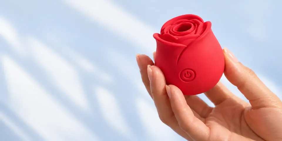 Red Roselle Classic rose toy held in a hand against a soft blue background